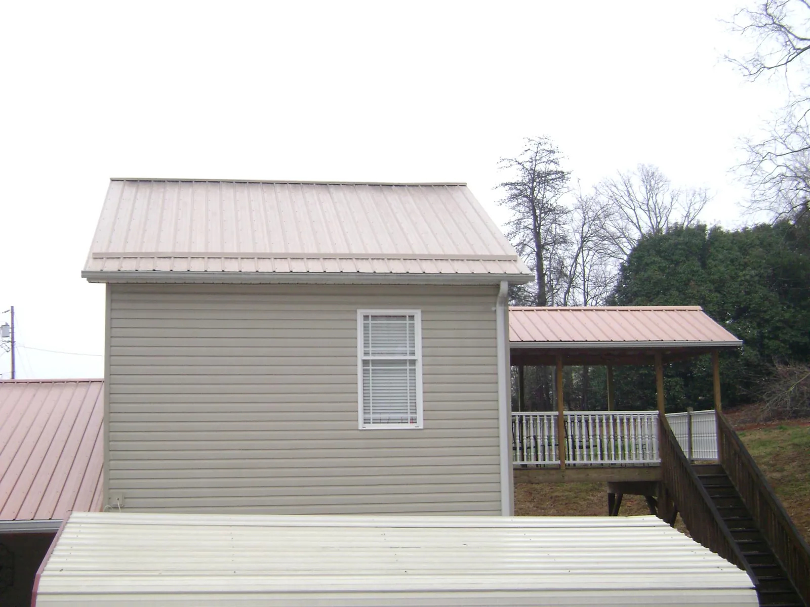 Tan metal roofs on a two story addition and attached porch, from a Roof Replacement job in Brilliant
