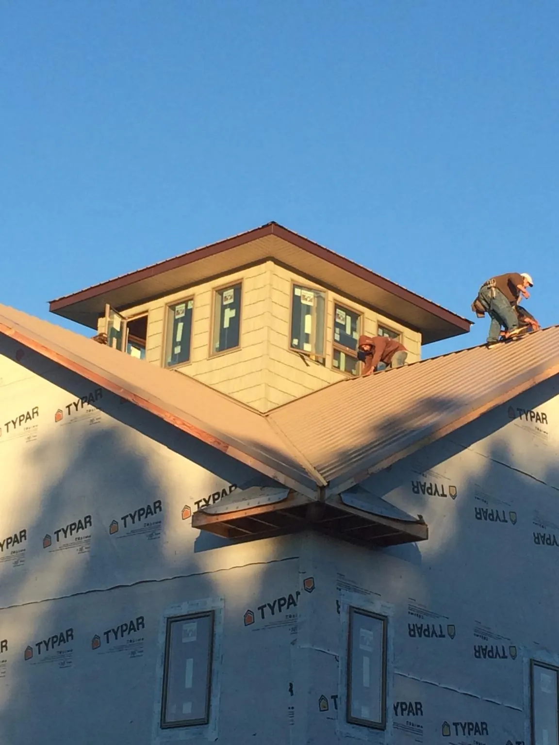 Roofers working around a rooftop cupola on a new metal roof at sunset — Roof Waterproofing in Brilliant by Roofing Brothers